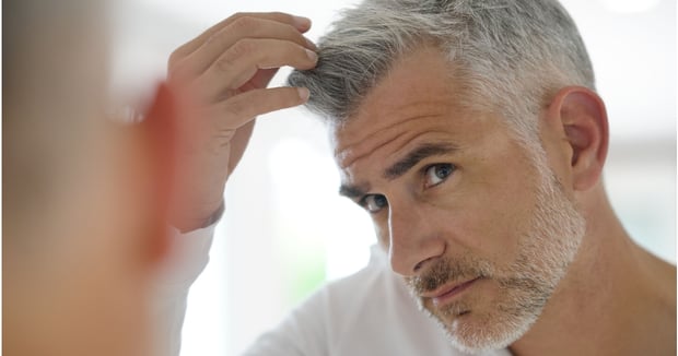 mature man with grey hair applying homemade hair gel to grey hairpiece